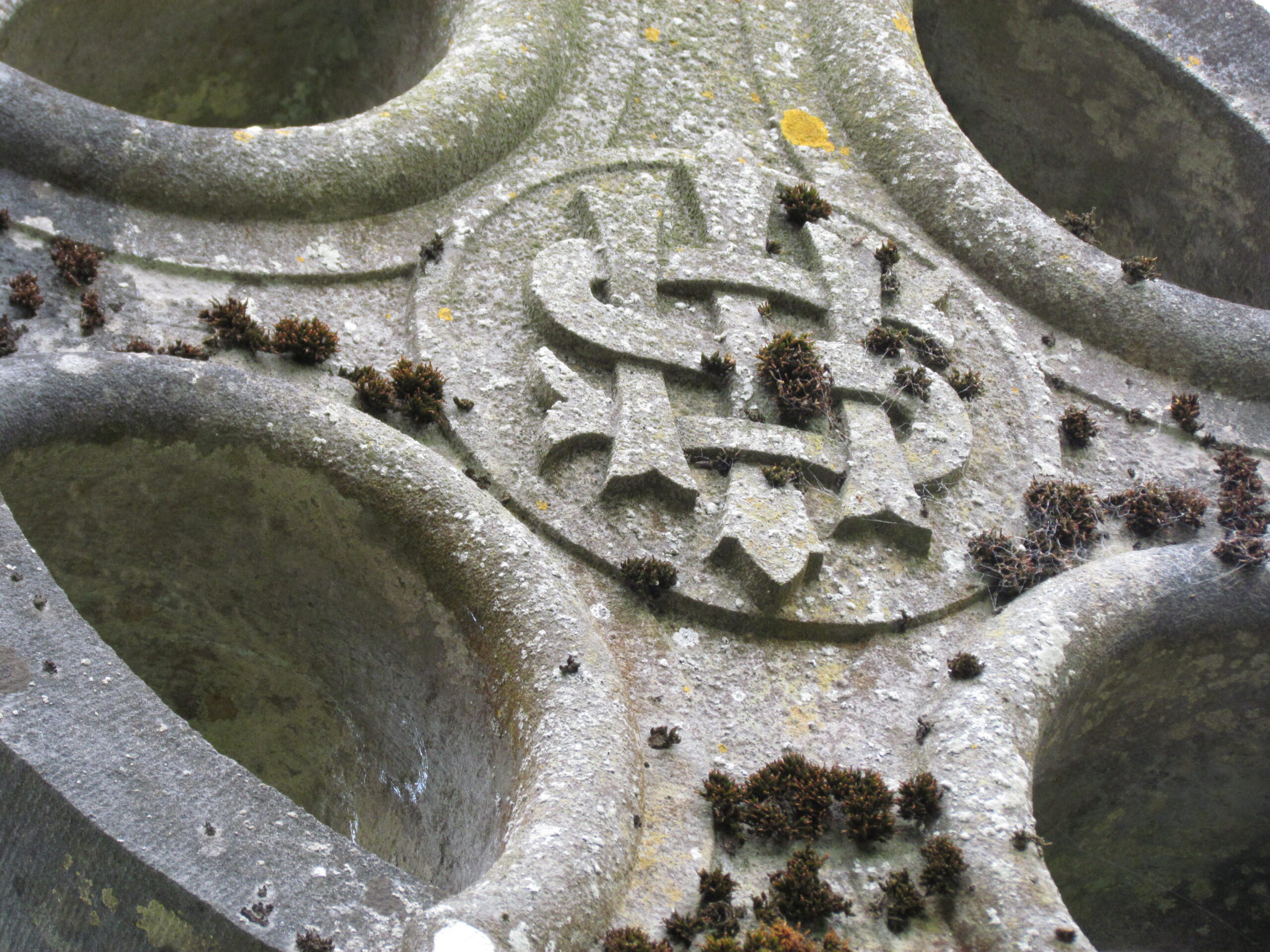 an old stone cross with lichen growing on it
