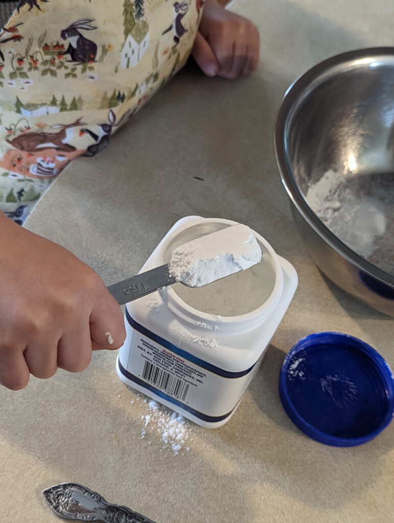 a kid scooping baking powder out of a container